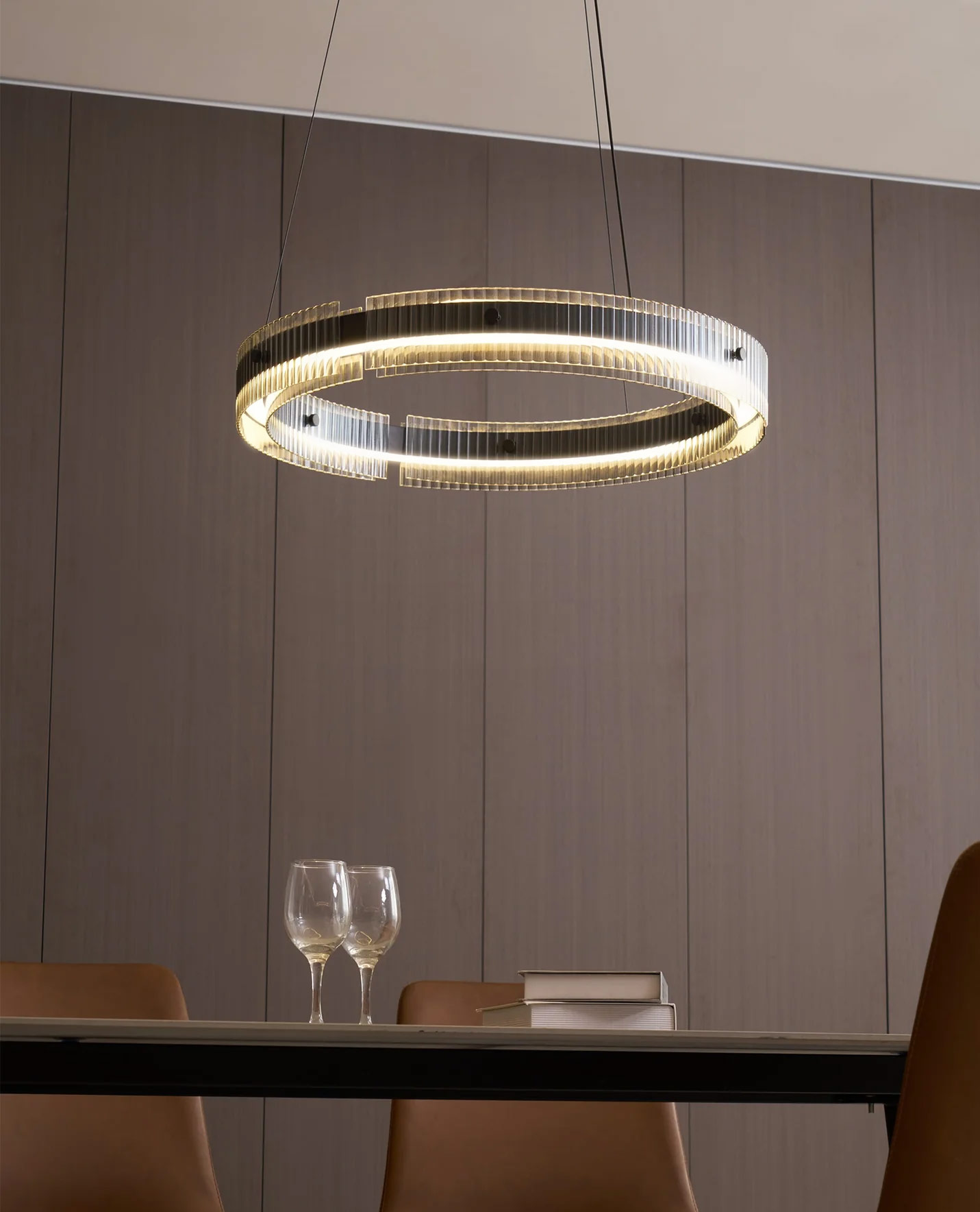 Modern black circular LED pendant light with ribbed glass diffuser and warm glow suspended above a marble dining table in a contemporary dining room.