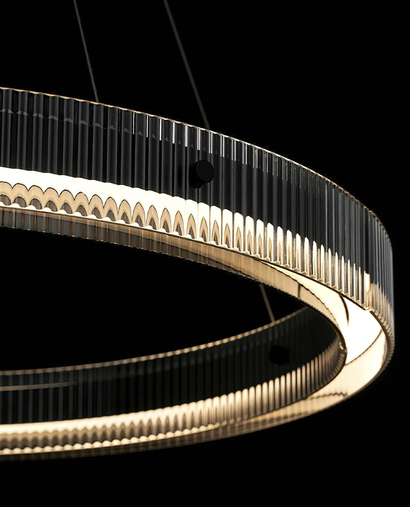Close-up of ribbed vertical glass panels and black aluminium frame on the modern circular LED pendant light, showing the layered halo glow.