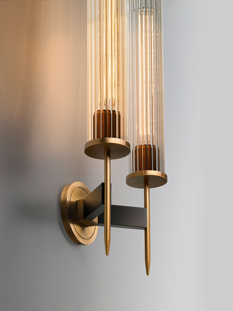 Avenel double wall sconce with two vertical ribbed glass shades and brass metal structure, angled view