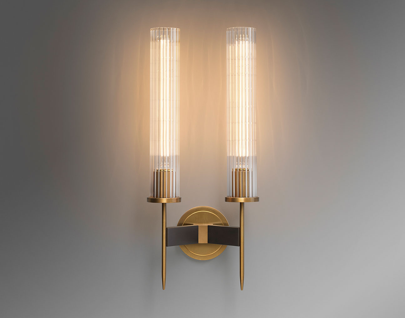 Front view of Avenel double wall sconce with symmetrical ribbed glass shades on a brass wall plate