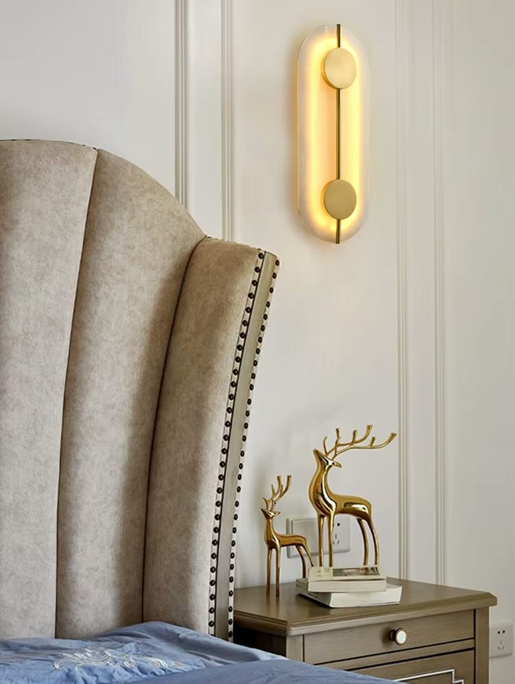 Oval brass and glass wall light mounted beside bed